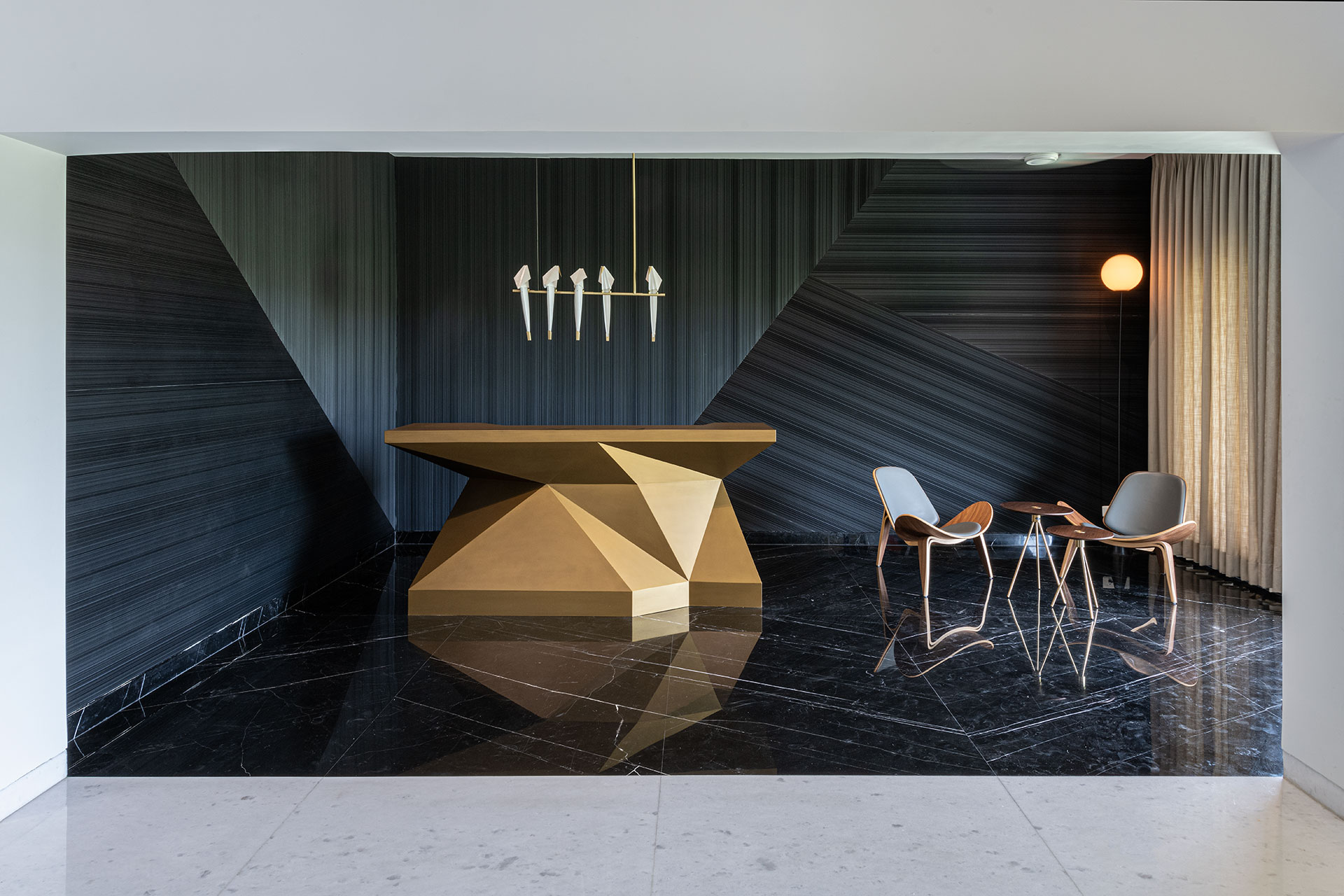 Open Bar-lounge area forms the focal point of this space, with its walls and floor contrasting visually from the white marble in deep grey, setting the backdrop for the custom designed faceted metallic finish plush high bar counter.