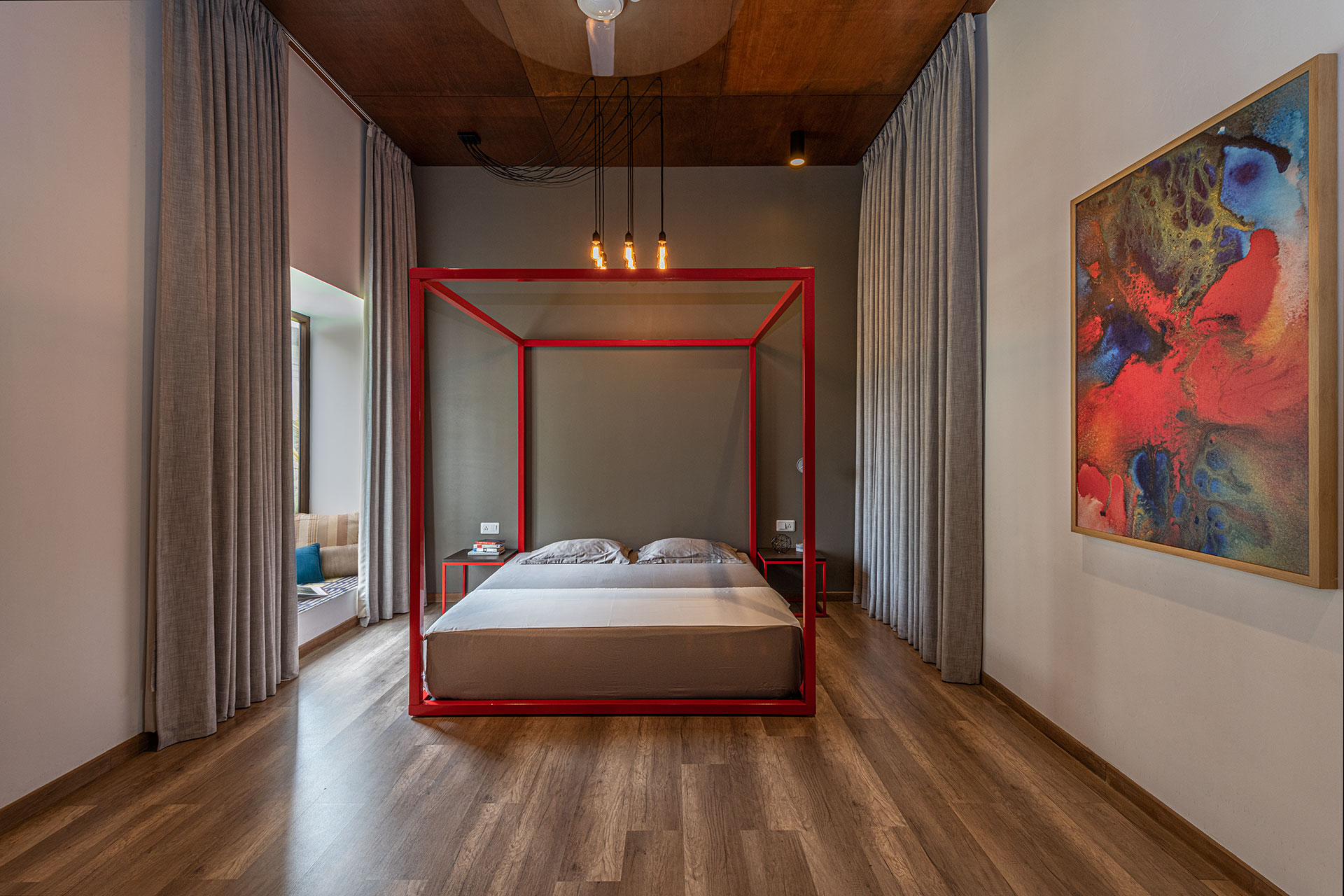The Red bedroom, with its four poster bed, and hanging light bulbs suspended from a ceiling of polished exposed plywood.