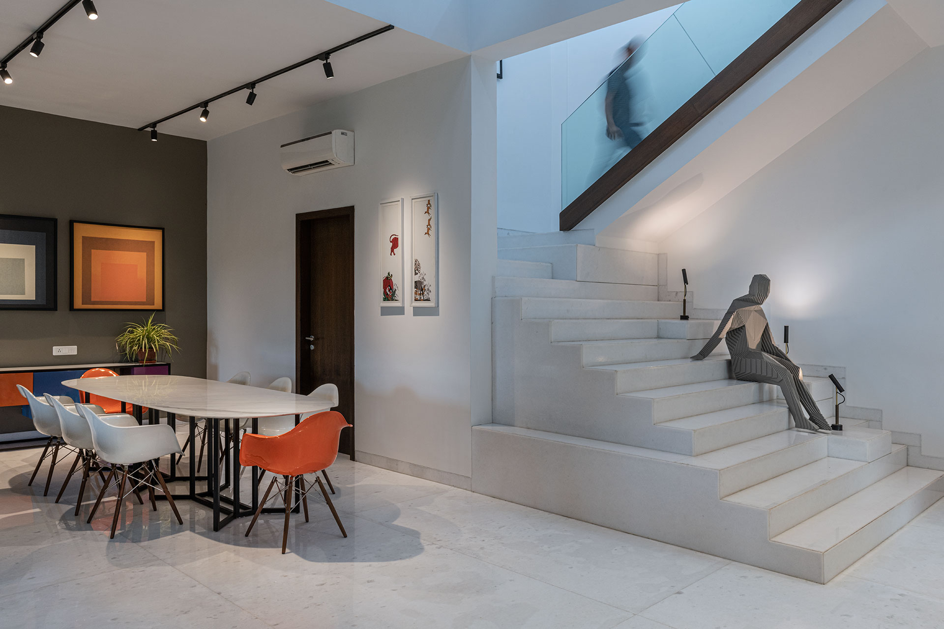 Monolithic white marble flooring turns and folds over the extended staircase treads and risers with a custom made faceted ‘human’ art installation created for this space.  The relaxed vibe exuded by the form of the cascading staircase is embodied by the ‘contemplating’ sitting human like sculpture.