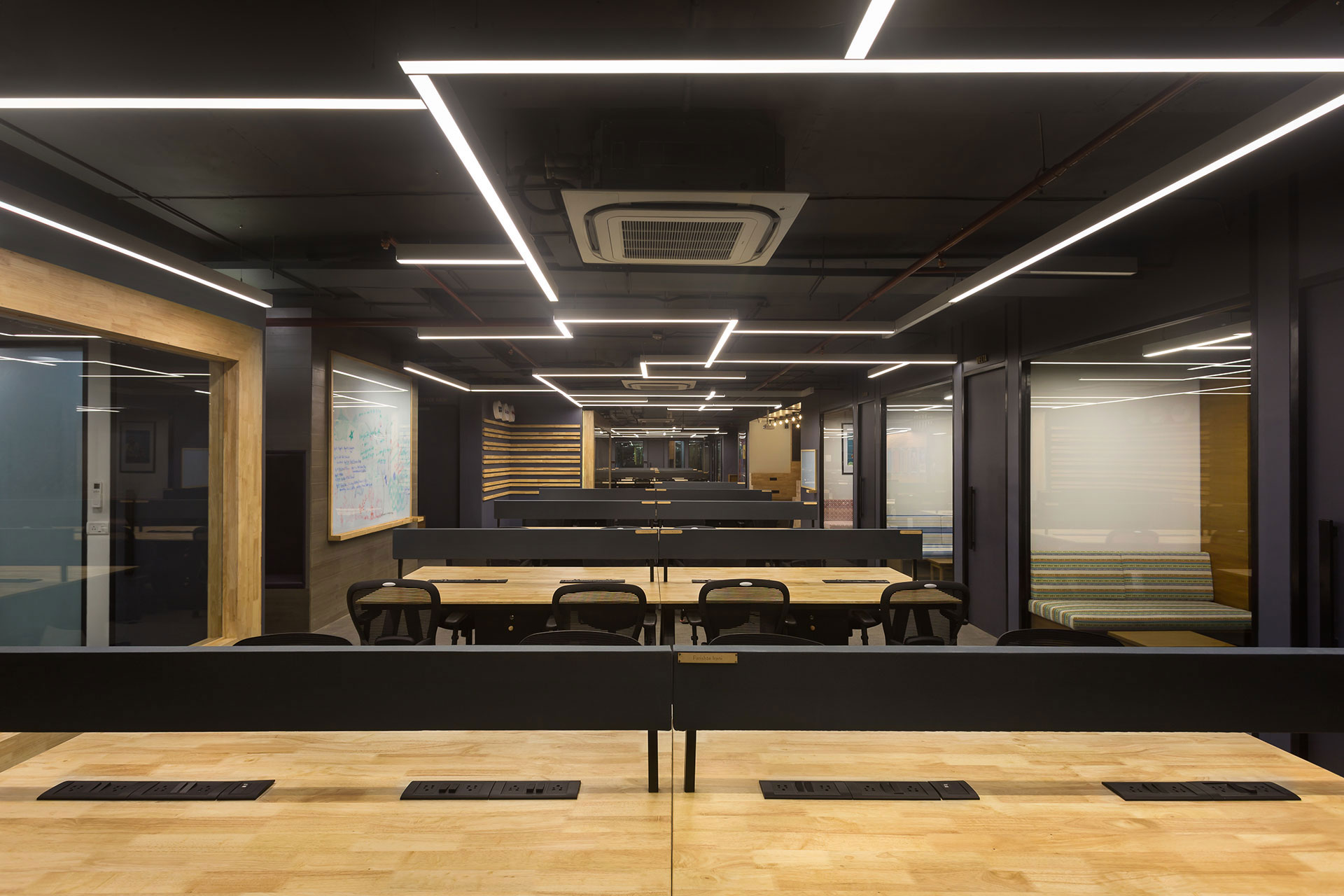Most of the secondary and tertiary functions are placed along the periphery allowing for a large central open tunnel for the workstations. The main work space area is kept clean and minimal using a  material palette consisting of hues of grey, black with rubber wood.