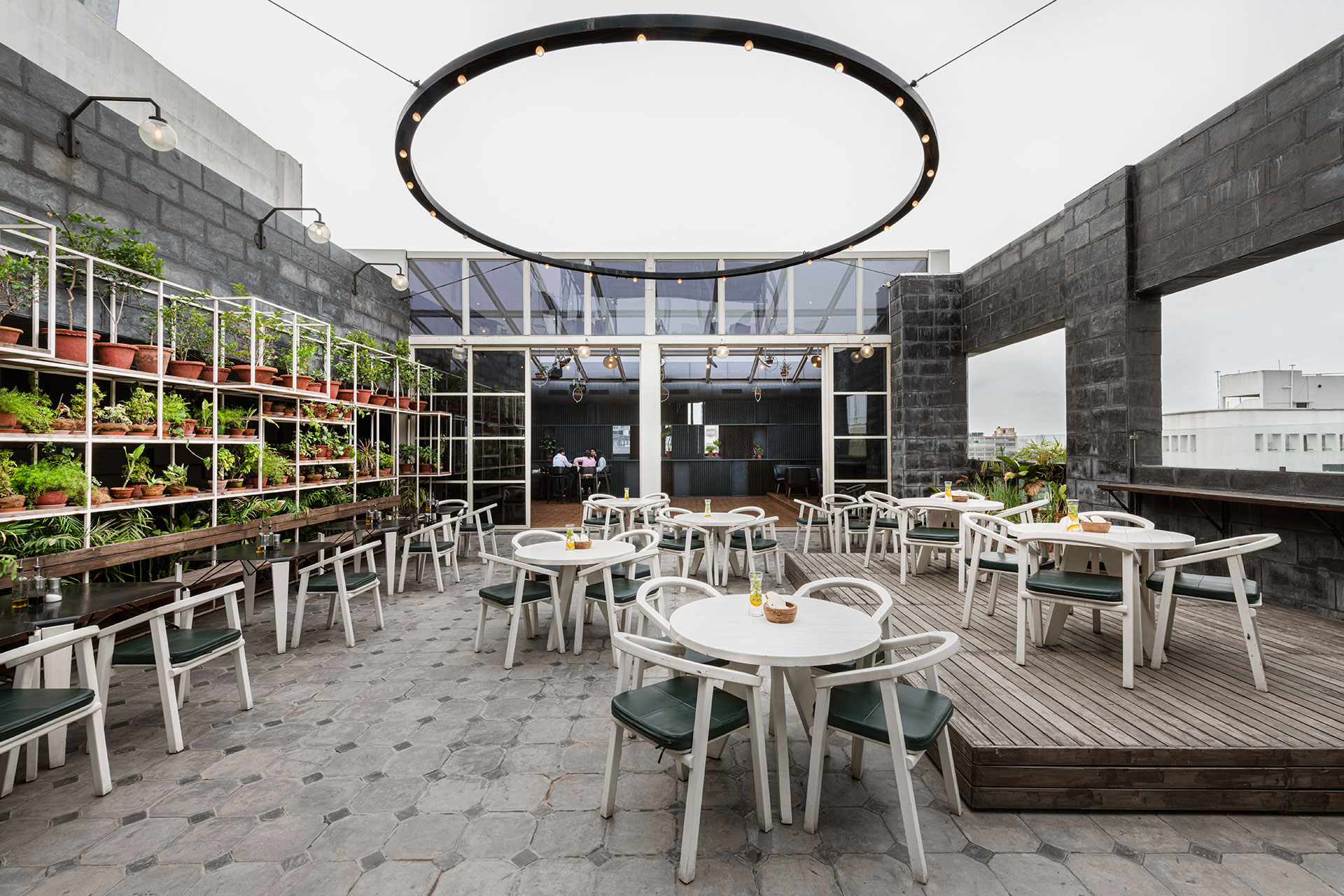 The central open to sky, roof-top courtyard, with its white furniture, live-performance wooden stage and herb-planter wall, exudes a relaxed vibe. Suspended above the courtyard is a large ring of lights.